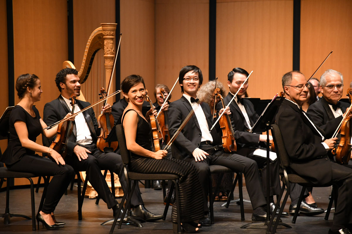 orchestra members back stage smiling for the camera