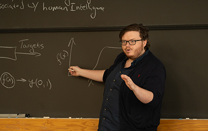 A photo of a faculty member teaching in front of a chalkboard