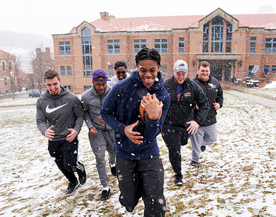 students playing a friendly game of football in the campus quad
