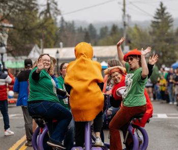A group of people wearing costumes on a bike during Hot Dog Day