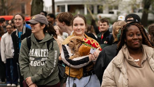 A girl holding a dog in a hot dog costume on Hot Dog Day