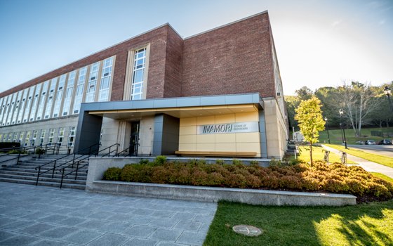 Modern brick building with large windows and a prominent entrance sign reading "Inamori School of Engineering." Surrounding greenery and clear blue sky create a welcoming atmosphere.