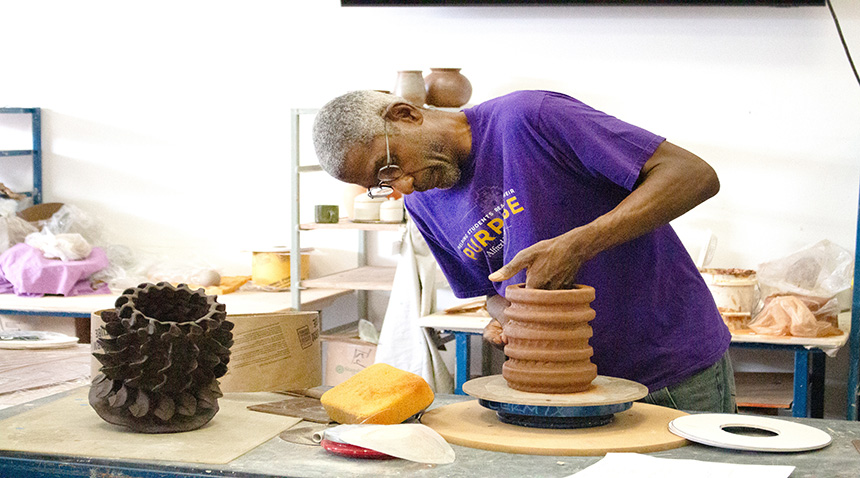 A photo of a professor crafting a clay pot