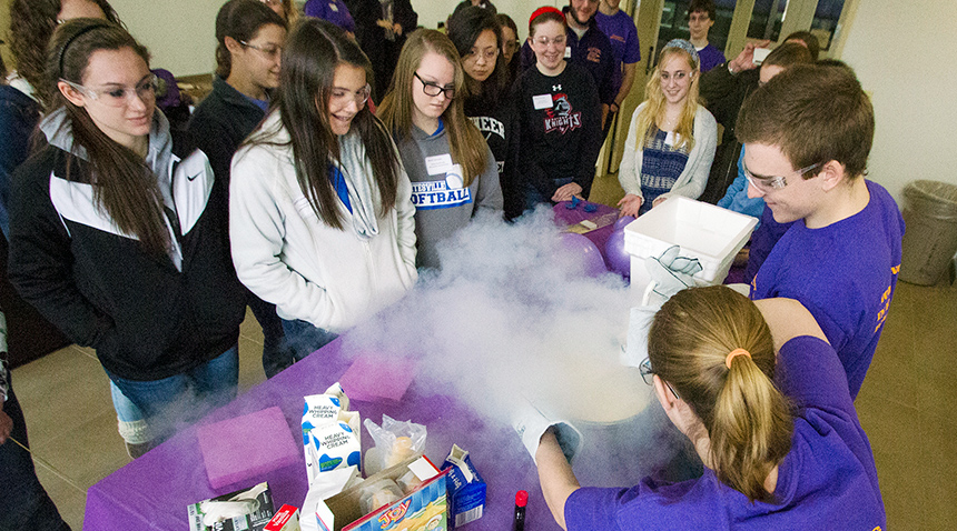 experiment being demonstrated at a table to group of young school children