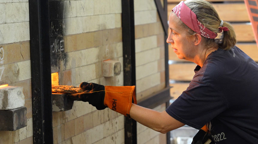 A photo of a student putting clay into a kiln