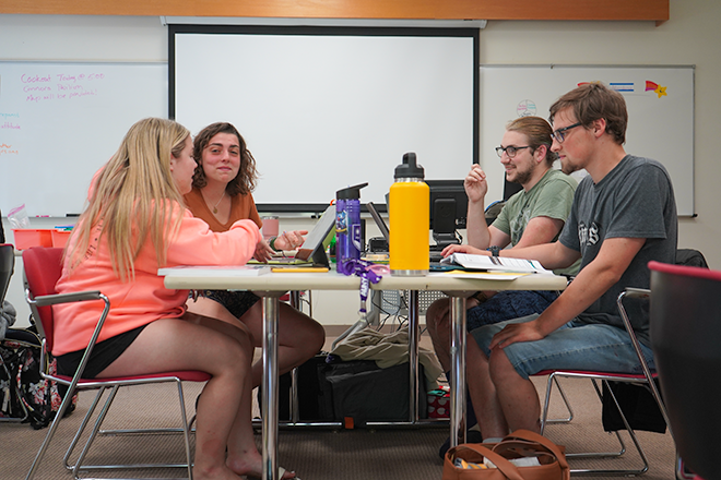 4 students at a desk in class