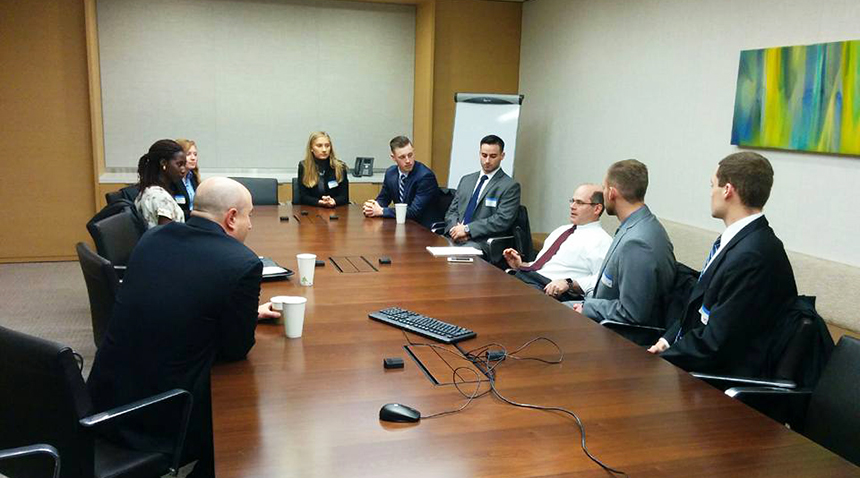 Business professionals and students sit around a conference table during a Business Executive Advisory Council meeting.