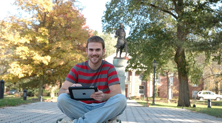 student sitting on the ground with a tablet
