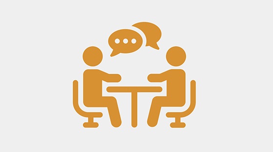 Icon of two people sitting at a table with speech bubbles above them, representing a discussion or appeals meeting.