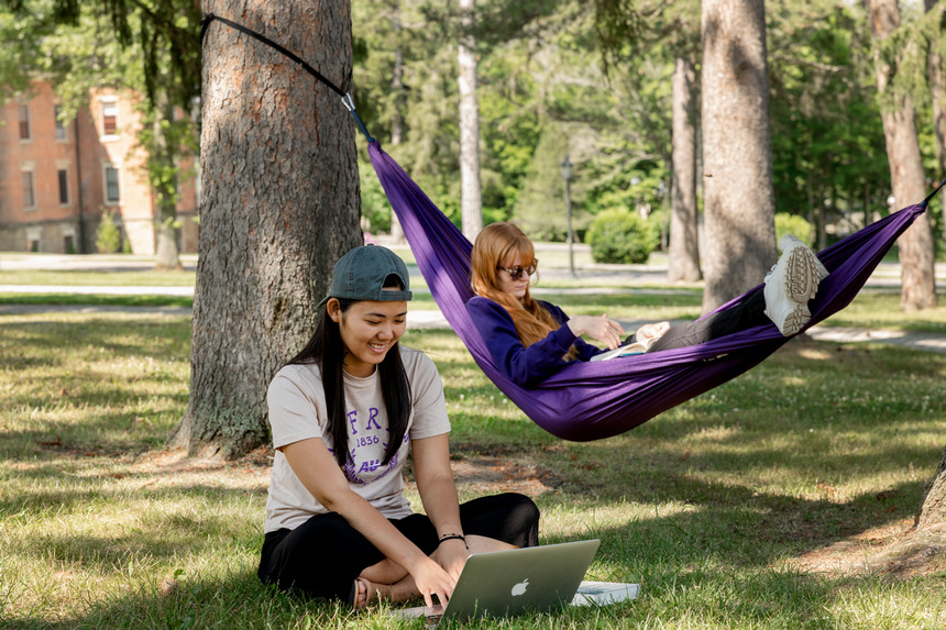 Students sitting on lawn and in hammock