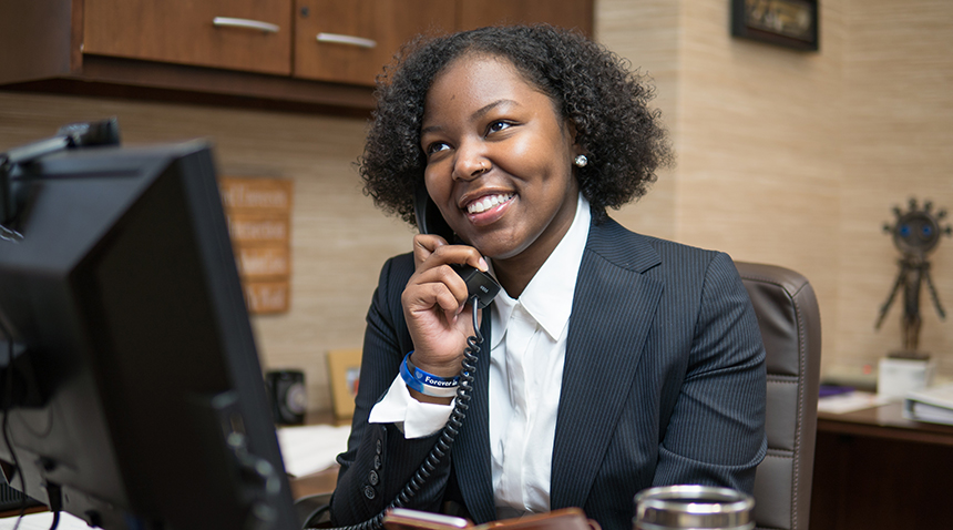 student at desk on the phone smiling