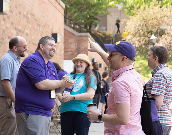 alumni chatting outdoors wearing AU shirts
