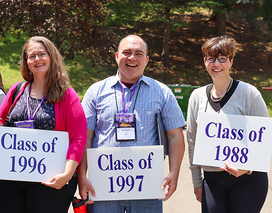 Alfred University alumni group photo holding grad year signs