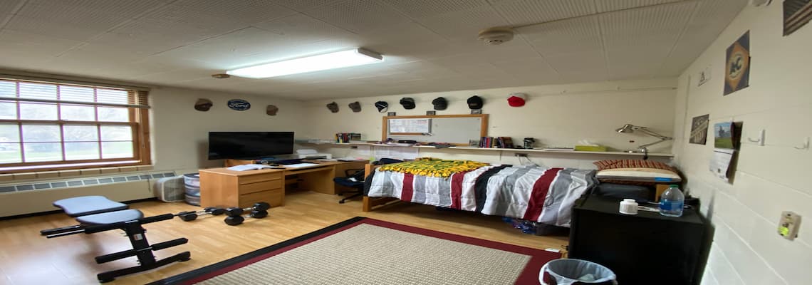 A student dorm room displaying a bed, desk, and television, illustrating a practical and inviting environment.