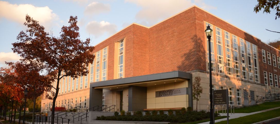 Exterior view of the McMahon Engineering Building at Alfred University during golden hour, with red brick walls, large windows, and a modern entrance labeled 'Inamori School of Engineering'.