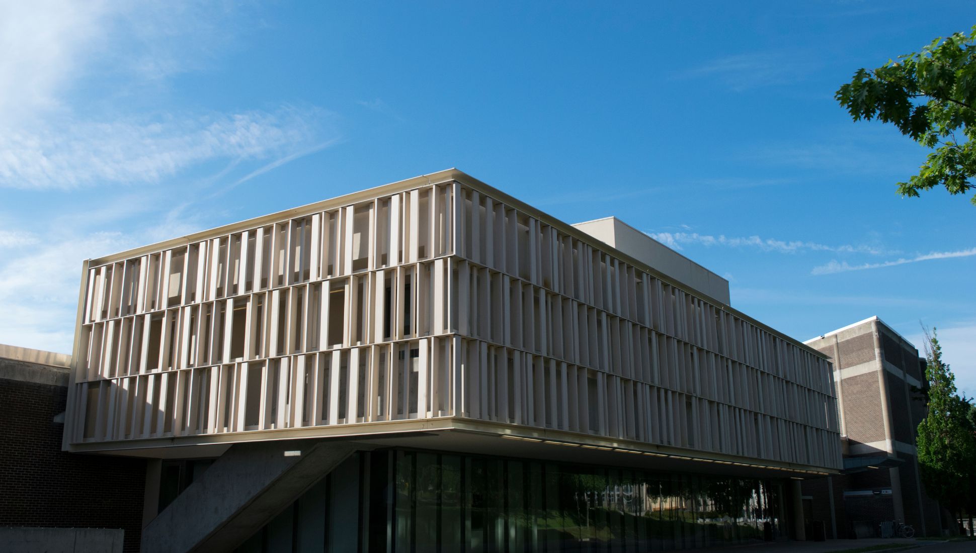 Modern academic building at Alfred University with vertical slatted facade and large glass windows, set against a clear blue sky.