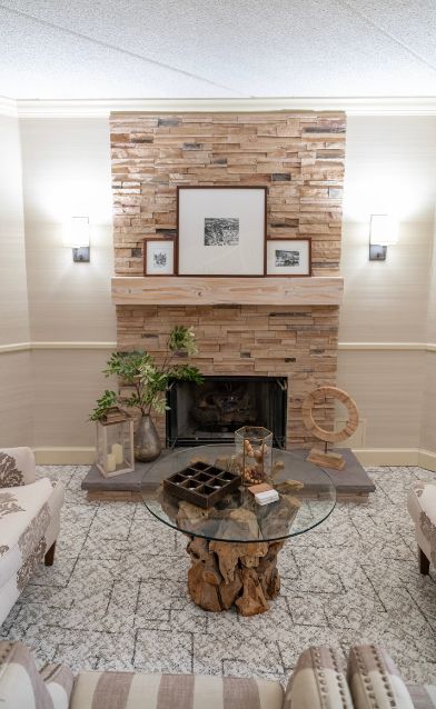 Fireplace setting at the Saxon Inn featuring a rustic brick mantel, framed artwork, decorative plants, and a unique glass coffee table with a natural wood base.