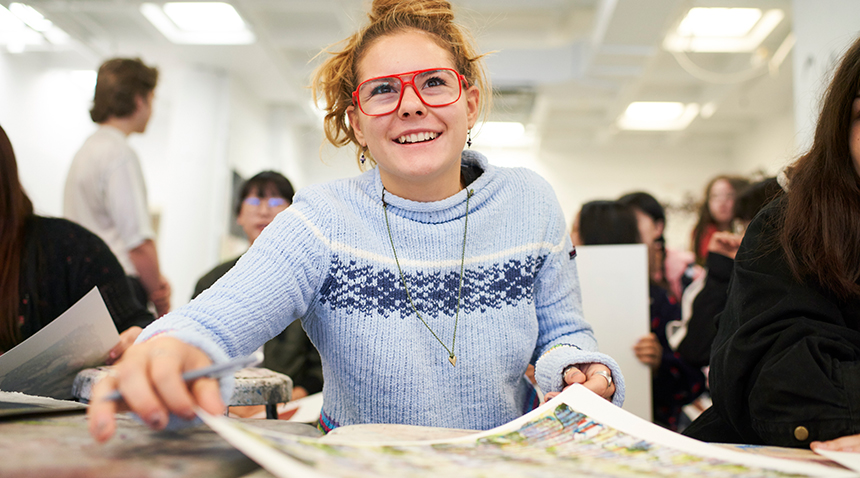 student smiling while working on an art piece