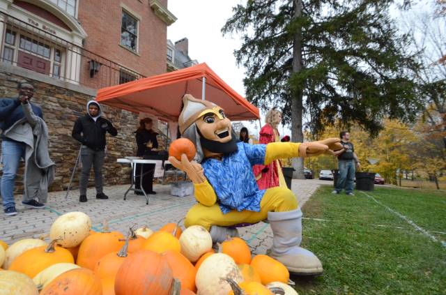 A photo of our mascot Lil' Alf holding a pumpkin in front of Brick lawn