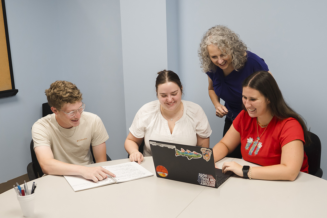 A photo of Alfred University business students in a classroom working with a professor