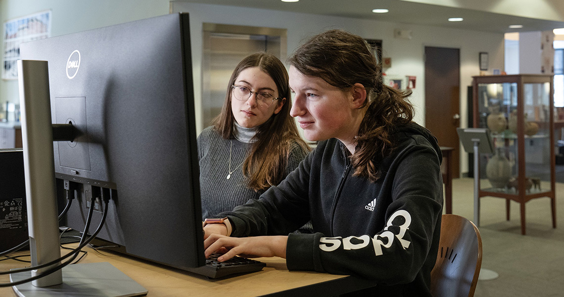 A photo of two Alfred University students working on a computer together in a lab