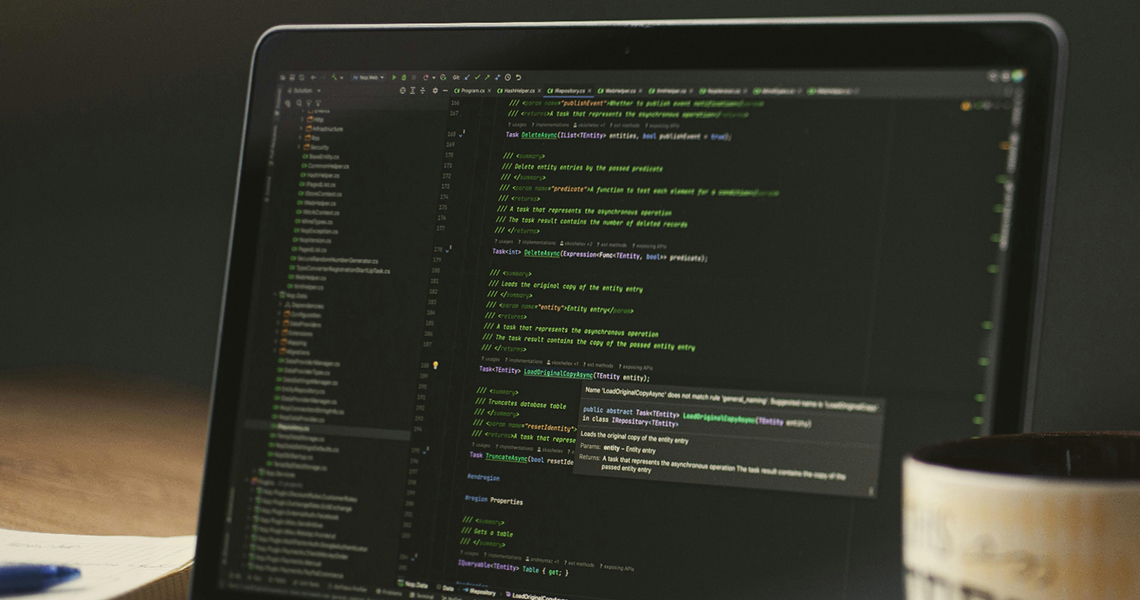 A photo of a laptop with HTML code on the screen and a cup of coffee next to it
