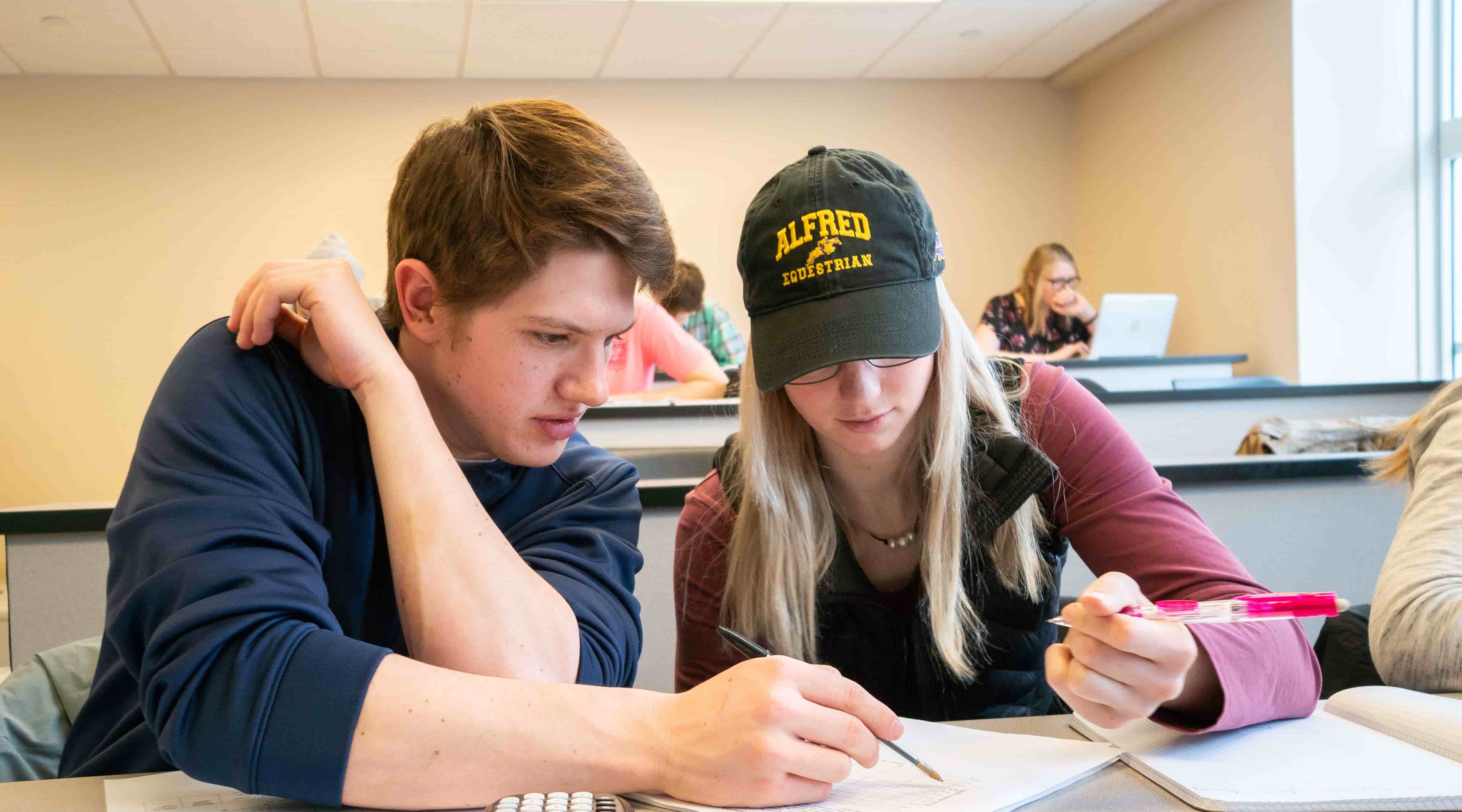 Male student helping female student in classroom