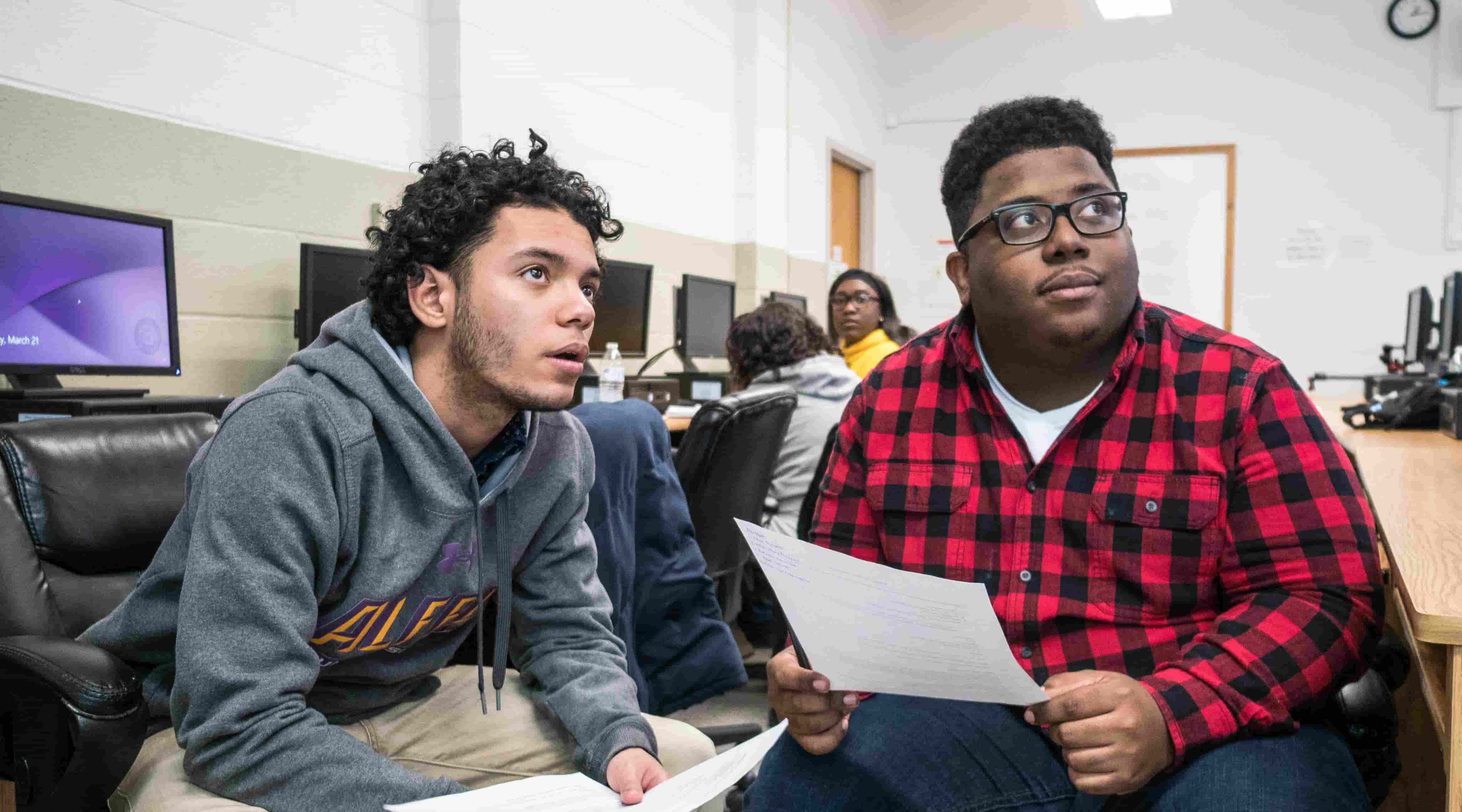 Two students listening to the instructor in a computer lab