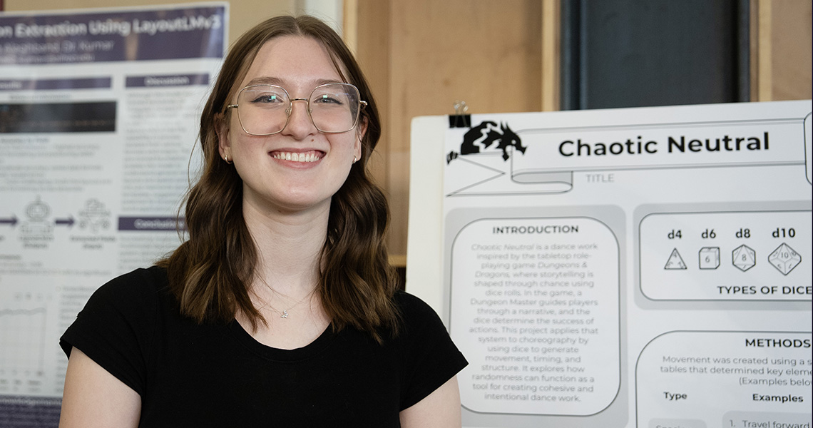 A photo of an Alfred University psychology student standing next to their research project poster