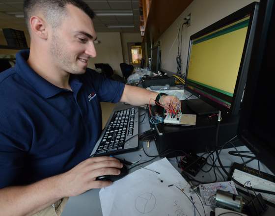 student working on a circuit board at a computer