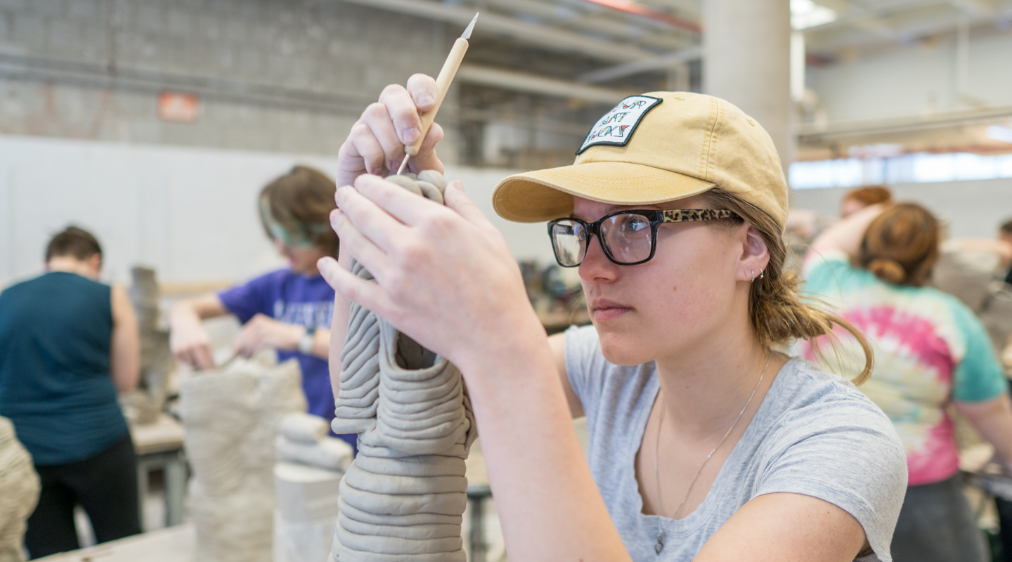student molding clay sculpture