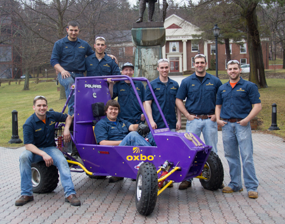 Group of Alfred University students posing with their purple Baja car on campus.