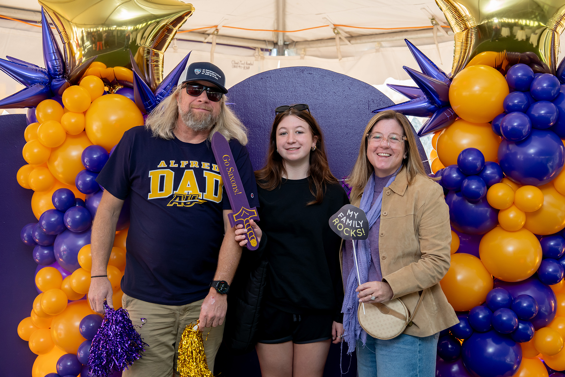 A photo of a college student with their parents during a Family Weekend event