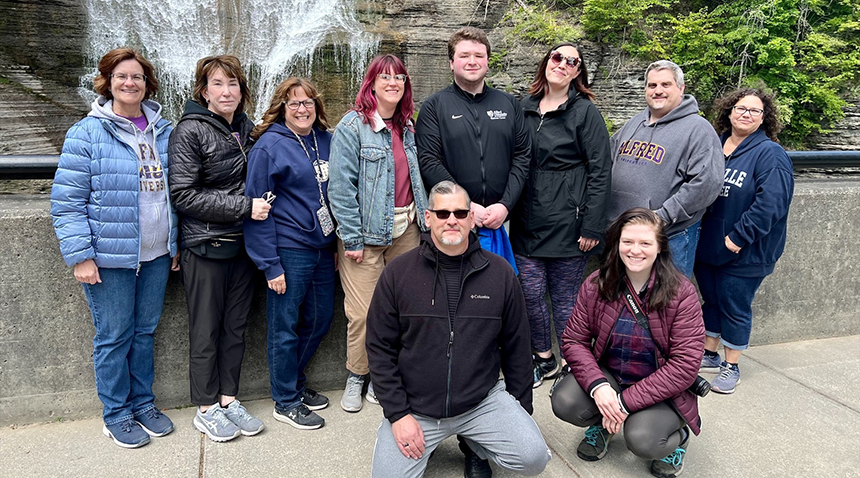Wellness Center staff smiling next to the Wellness Center Sign