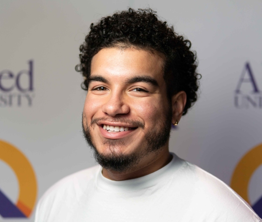 Justin smiling in front of apex logo backdrop