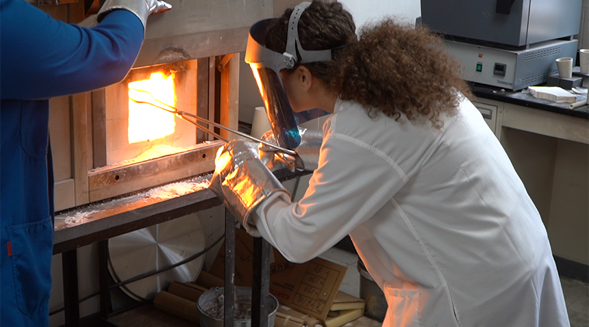 student working with materials in a fire oven