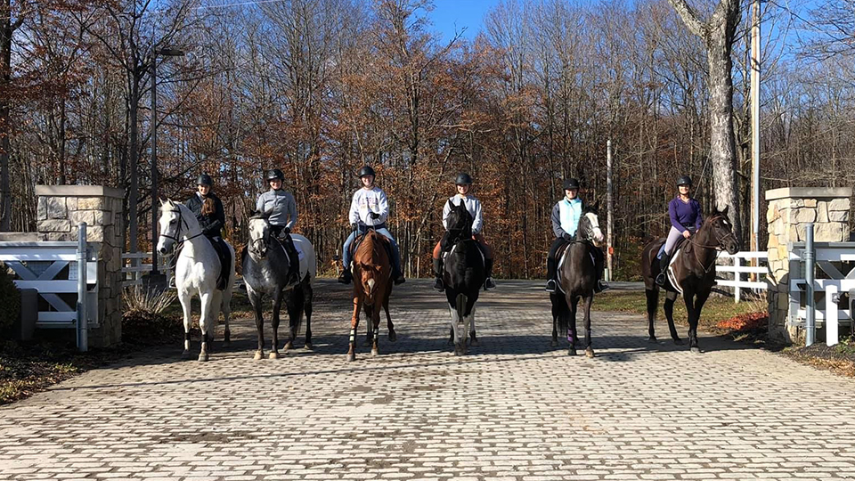 6 riders on their horses outside of the equestrian center