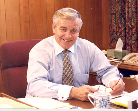 man in shirt and tie sitting at desk