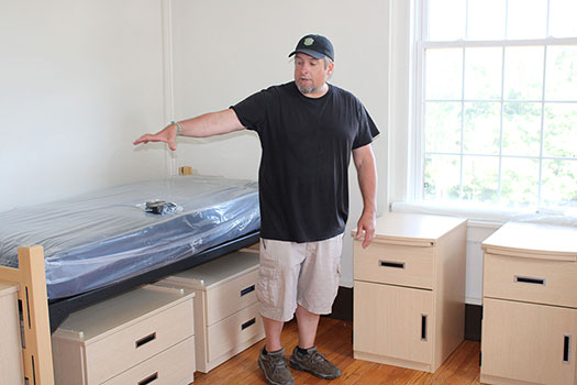 Matt Yuhas '94 shows off some furniture in a newly renovated Brick residence hall room