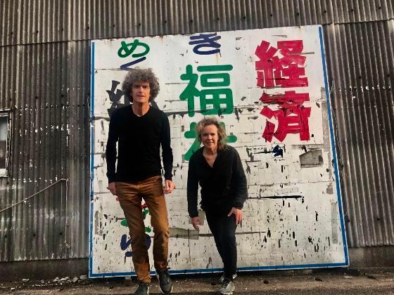 heringa and van kalsbeek in front of a large wall covered in artistic graffiti