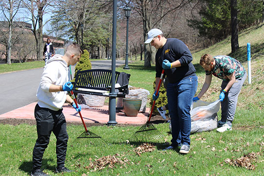 photo of three students cleaning up leaves