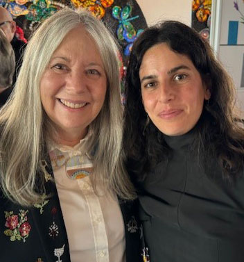 two women smiling, one with long gray hair, one with black hair