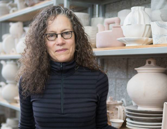 headshot of woman with glasses in front of pottery