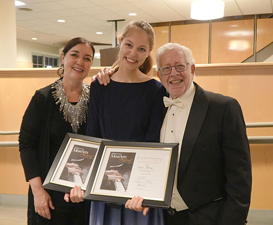 young girl with award certificates with woman and older man