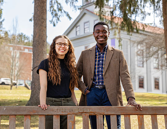 photo of two students standing behind a park bench