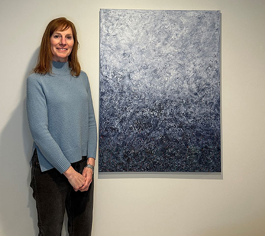 woman standing next to a painting
