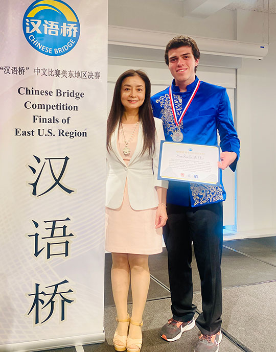 woman and man standing next to a sign, man holding award certificate