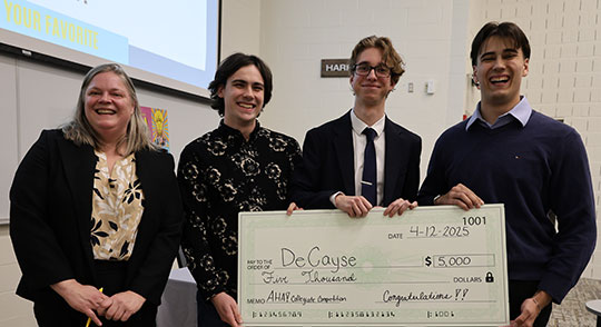 a women and three young men holding a giant check