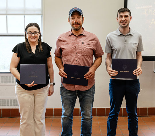 three people standing in a line holding certificates