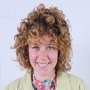headshot of a woman with curly red hair, smiling